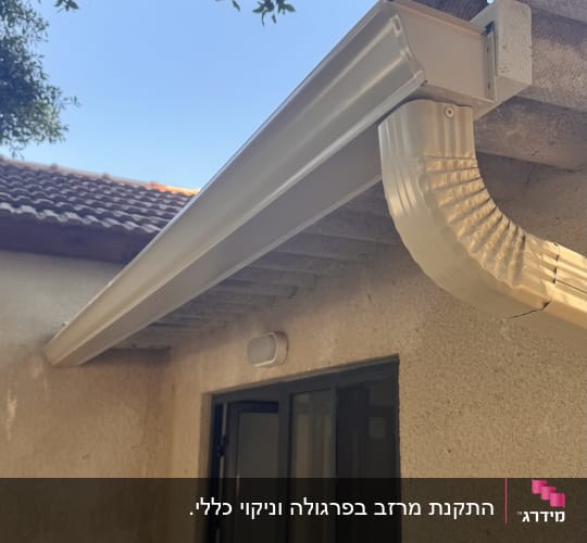 מרזב מחובר לגג בית עם עצים ברקע